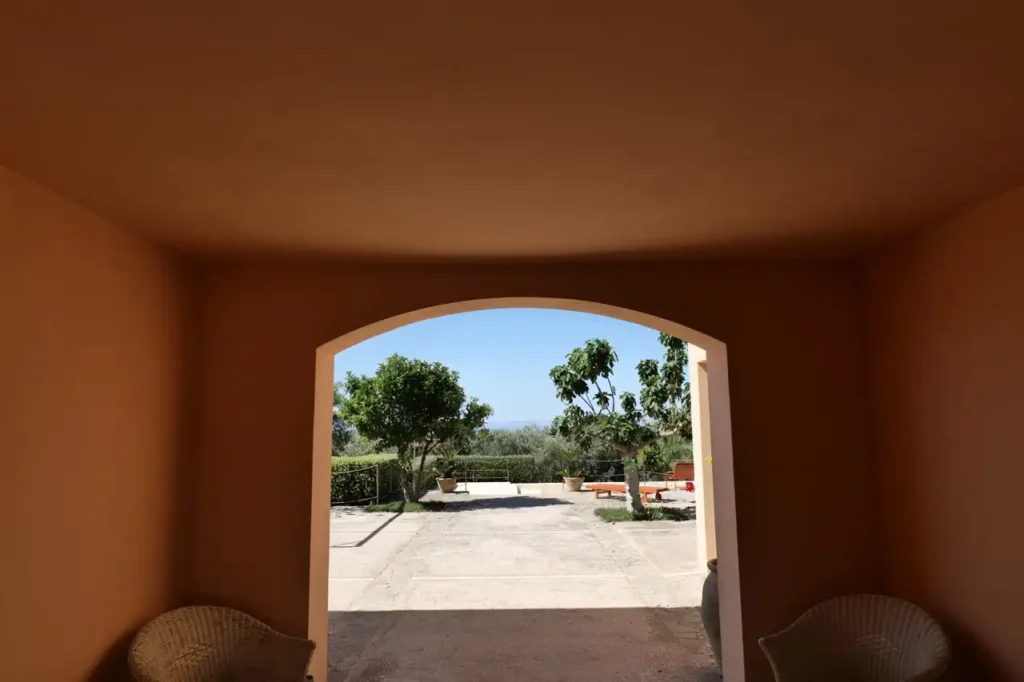 Experience a luxury yoga retreat in Sicily at La Segreta, surrounded by iconic Italian architecture and serene landscapes with the ocean in the distance.