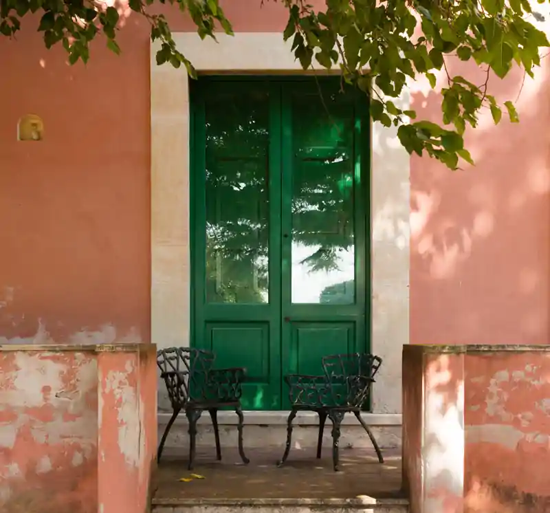 Corporate retreats in Sicily a beautiful sicilian green door, with a nice table and a tree 