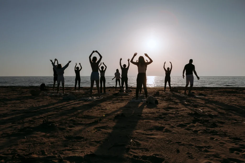 yoga trips enjoying with friends on the beach in a sundown, saluting the sun